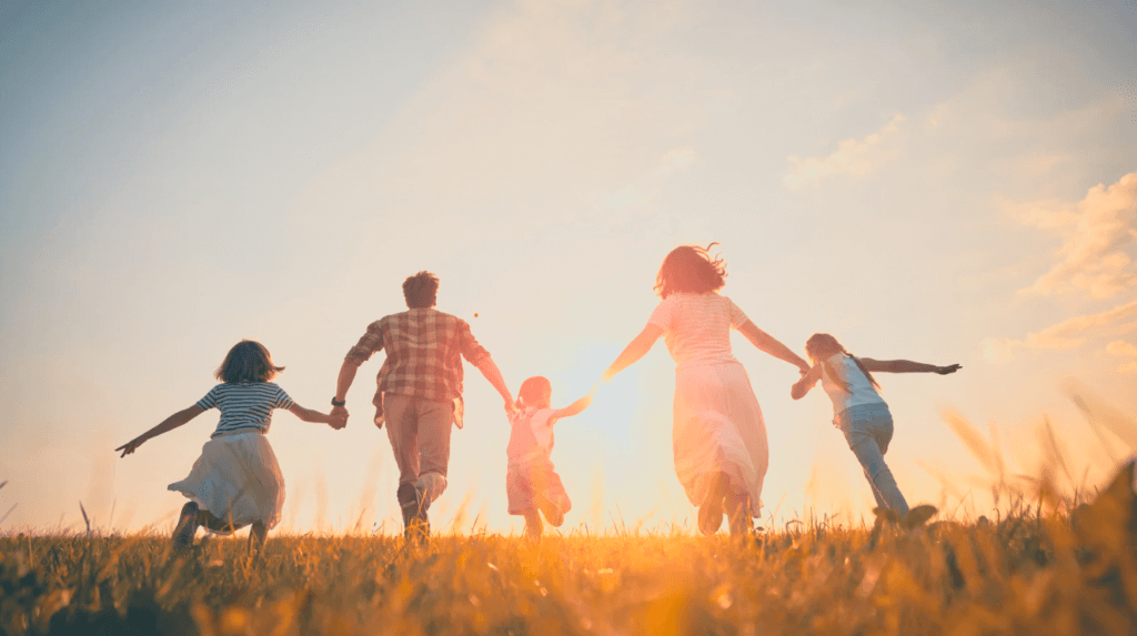 rodicia s dvoma detmi bezia po luke v ustrety slnku